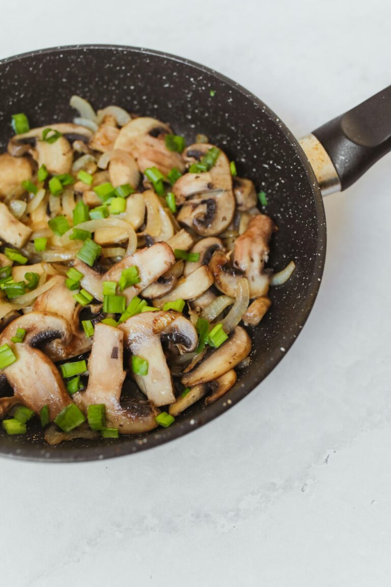 Delicious sautéed mushrooms and onions with herbs in a non-stick frying pan.